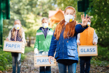 Against pollution. Nice red haired girl wearing a mask while showing her hand to you