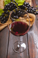 wine with branches of white grapes. On a wooden table.