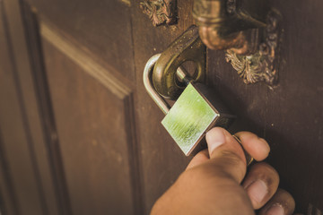 The old wooden door is locked with a silver lock, unlocked with a hand lock.