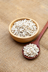 Organic Jobs tears seed in round wooden bowl and wooden spoon on hessian fabric background, natural product, vegetarian food