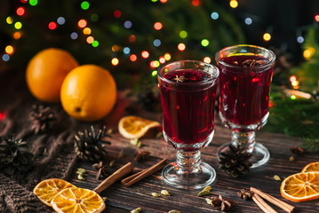 two glasses with mulled wine on the table with orange slices and spices with winter Christmas decor
