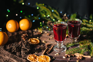 Fototapeta na wymiar two glasses with mulled wine on the table with orange slices and spices with winter Christmas decor