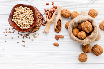 Various legumes and different kinds of nuts set up on white wooden table.