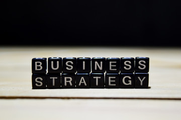 Business Strategy concept wooden blocks on the table. With personal development and motivation concept on blurred or black background