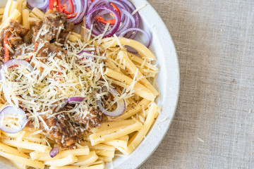 Pasta genovese - casarecce with genovese-style beef sauce in a white plate on a rustic background, copy space for a recipe
