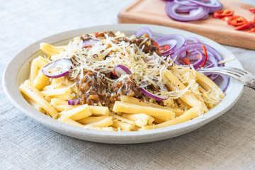 Pasta genovese - casarecce with genovese-style beef sauce in a white plate on rustic background