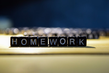 HOMEWORK concept wooden blocks on the table. With personal development and motivation concept on blurred or black background