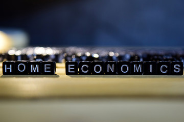 HOME ECONOMICS concept wooden blocks on the table. With personal development and motivation concept on blurred or black background
