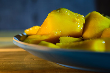 Close-up mango in blue plate on wooden table. Health inspiration concepts. Vintage Background