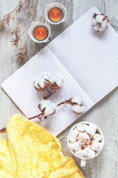 Cup of coffee and marshmallow, candles, cotton plant flower branches, notepad