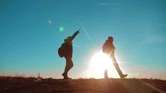 Two hikers with backpacks climbing a peak on cloud sky background