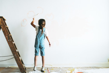 Young girl painting the walls pink