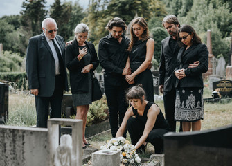 Family laying flowers on the grave - obrazy, fototapety, plakaty