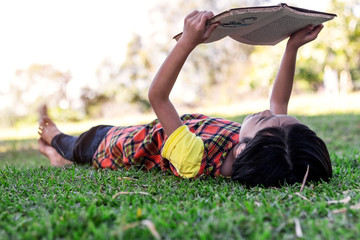 Cute little girls lying on the grass reading a book in garden at summer time