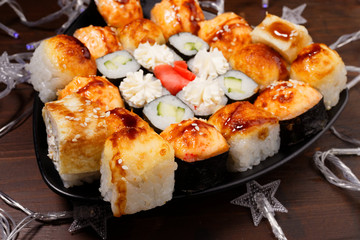 New Year's assortment of sushi on a black plate, with garlands. Christmas New Year sushi set.