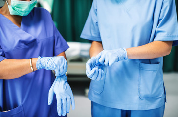 Surgeons wearing gloves preparing for surgery - Powered by Adobe
