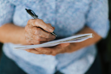 Senior woman writing down her memories into a notebook