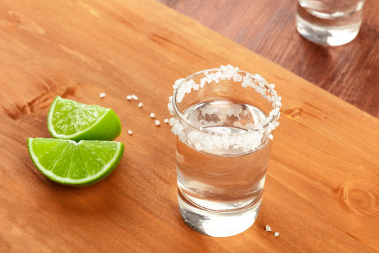A phto of a tequila shot with lime on a rustic wooden background with a place for text