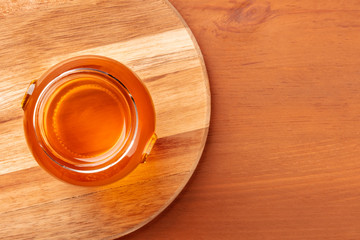 A photo of a vibrant jar of organic honey, shot from above on a rustic wooden background with a place for text