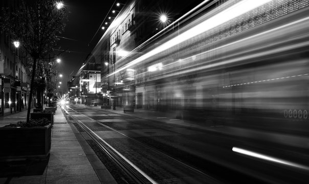 Light trails of a tram driving a street by night (black & white)