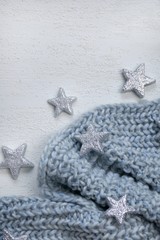 Fototapeta na wymiar Winter holiday background. gray knitted scarf and silvery decorative stars 