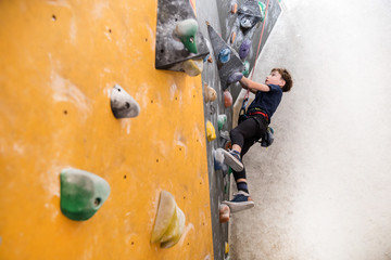 little boy climbing a rock wall
