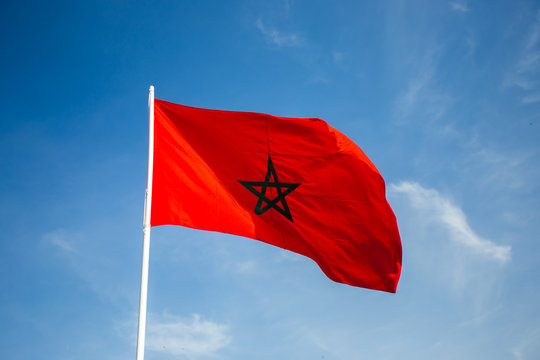 Morocco flag floating in the wind with a blue sky background.