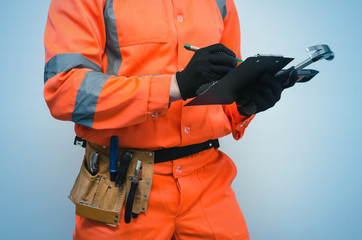 The measurer worker writes dimensions to his notebook. Building contract signing. Builder with construction project plans in the hands isolated on blue background.