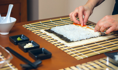 Chef hands placing ingredients on rice to make sushi © David Pereiras