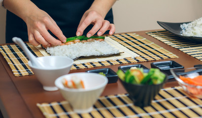 Chef hands placing ingredients on rice to make sushi