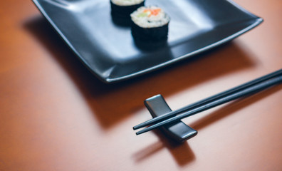 Japanese chopsticks and hashioki next to sushi plate