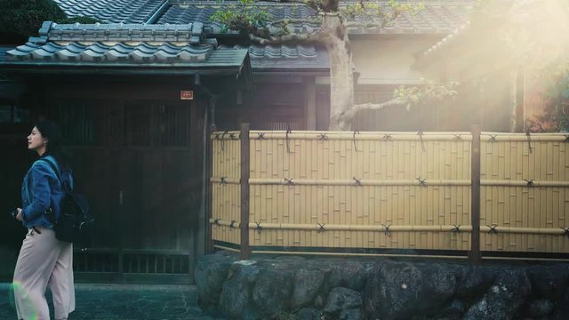 elegant lady walking on the street next to the Japanese style house and flicks her long black hair