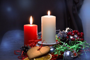 Christmas composition: red and white burning candles on a festive table on a dark background. Gingerbread, tinsel, festoon. Christmas, New Year, holiday