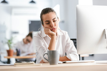 Confused bored young business woman work in the office with computer.
