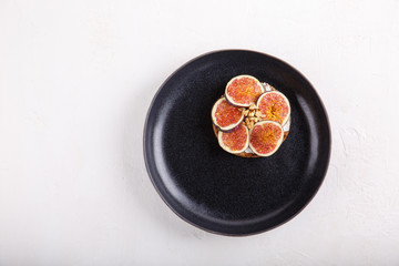 Whole grain bread sandwich with figs and walnuts on white background.