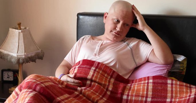 Depressed female cancer patient lying in bed