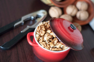 peeled walnuts in a small red saucepan with a nutcracker