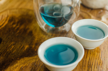 Organic blue tea Anchan in a teapot and a cups on wooden background