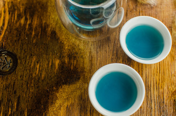 Organic blue tea Anchan in a teapot and a cups on wooden background