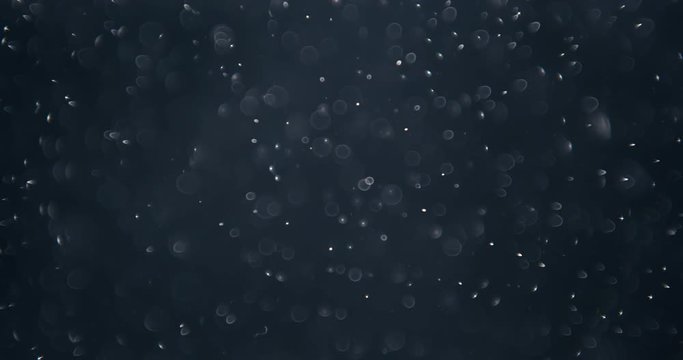 Particles and ink slowly moving in water on black background