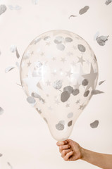 Transparent balloon with stars and confetti in the hands of a woman