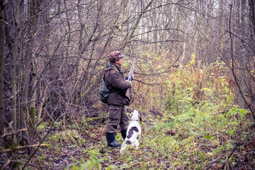 male hunter, in the forest, with arms, dog Springer Spaniel, hunting, autumn