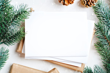 Merry Christmas and happy New year. Mockup with postcard and branches of a Christmas tree on white background. Background with copy space. Top view. Christmas background. Horizontal.