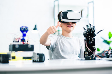 Enthusiastic little boy experimenting with robotic hand at home