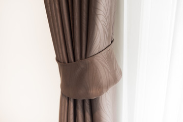 Part of beautiful draped brown curtain on the door at home. Close up of piled curtain, home decoration.