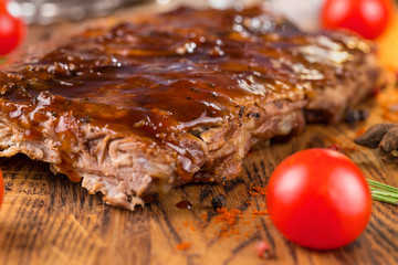 Delicious barbecued ribs seasoned with a spicy basting sauce on an old rustic wooden chopping board...