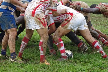 Detail of rugby players having fun in a muddy field.