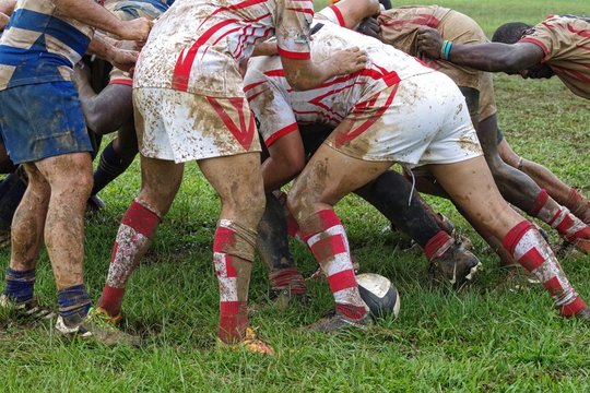 Detail of rugby players having fun in a muddy field.