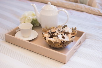 Morning lifestyle. A wooden tray with a cup of tea and dry flower on the bed.