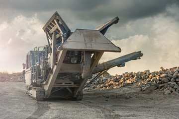Excavator and machine to pulverize stone in a quarry - obrazy, fototapety, plakaty